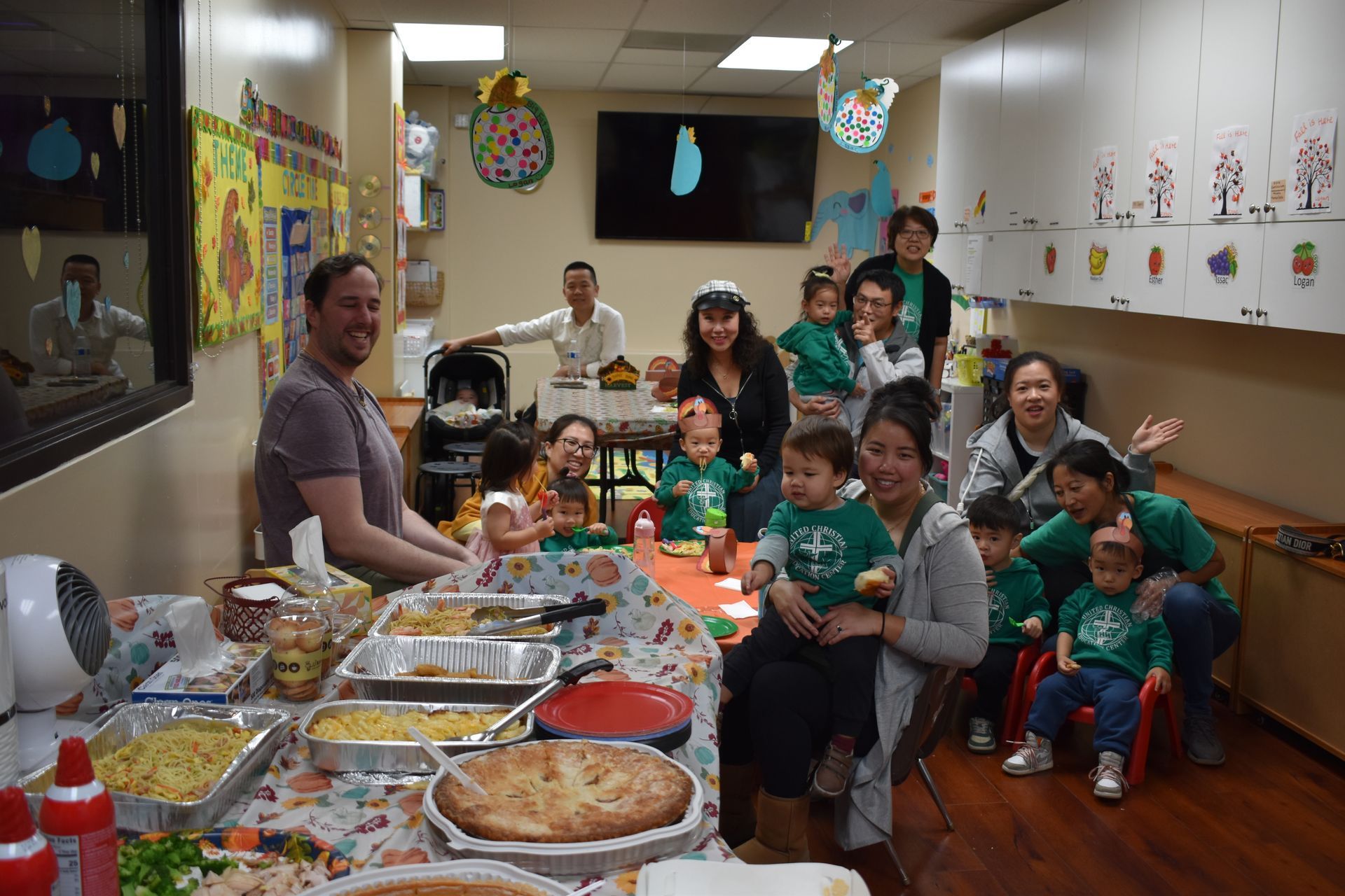 People, including young children, gathered around a table with food, likely at a party or event.