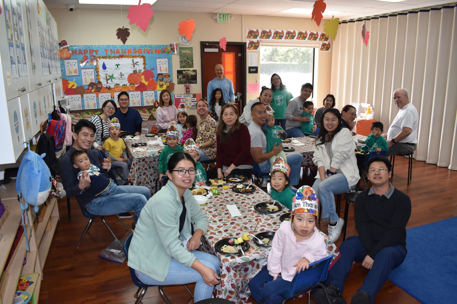 A group of people sitting around tables in a room, celebrating. Decorations and children present.