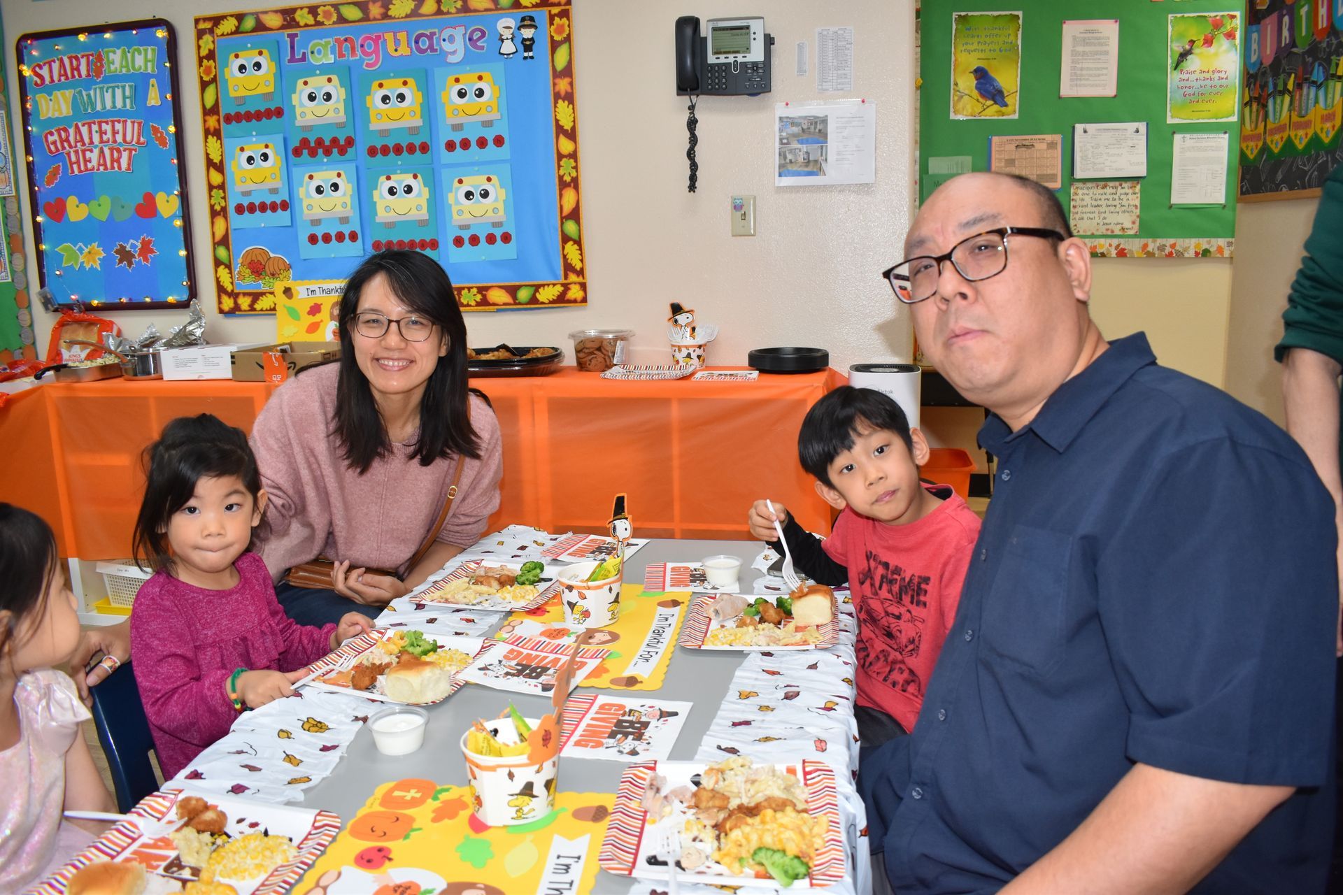 People at a decorated table, including a woman, a man, and children, likely at a school event.