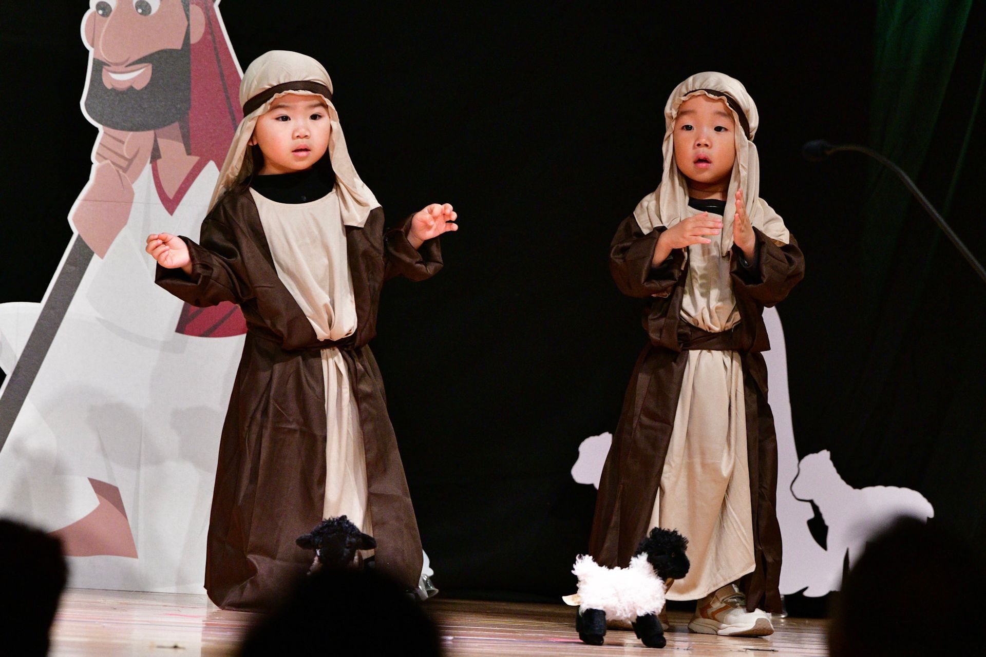 Two children in shepherd costumes performing on stage.