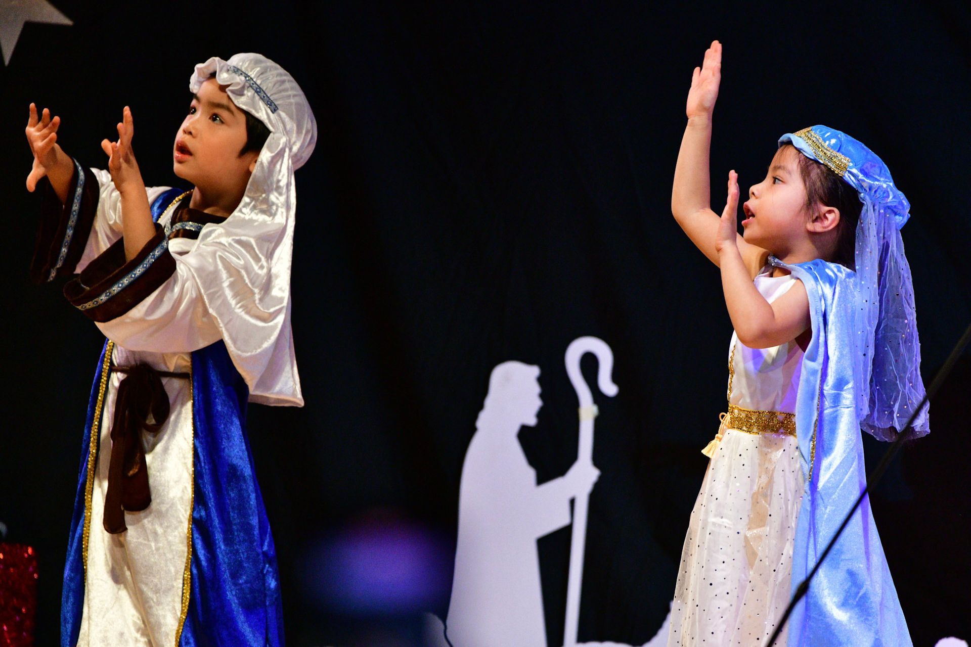 Two children in costumes perform a play on a stage.