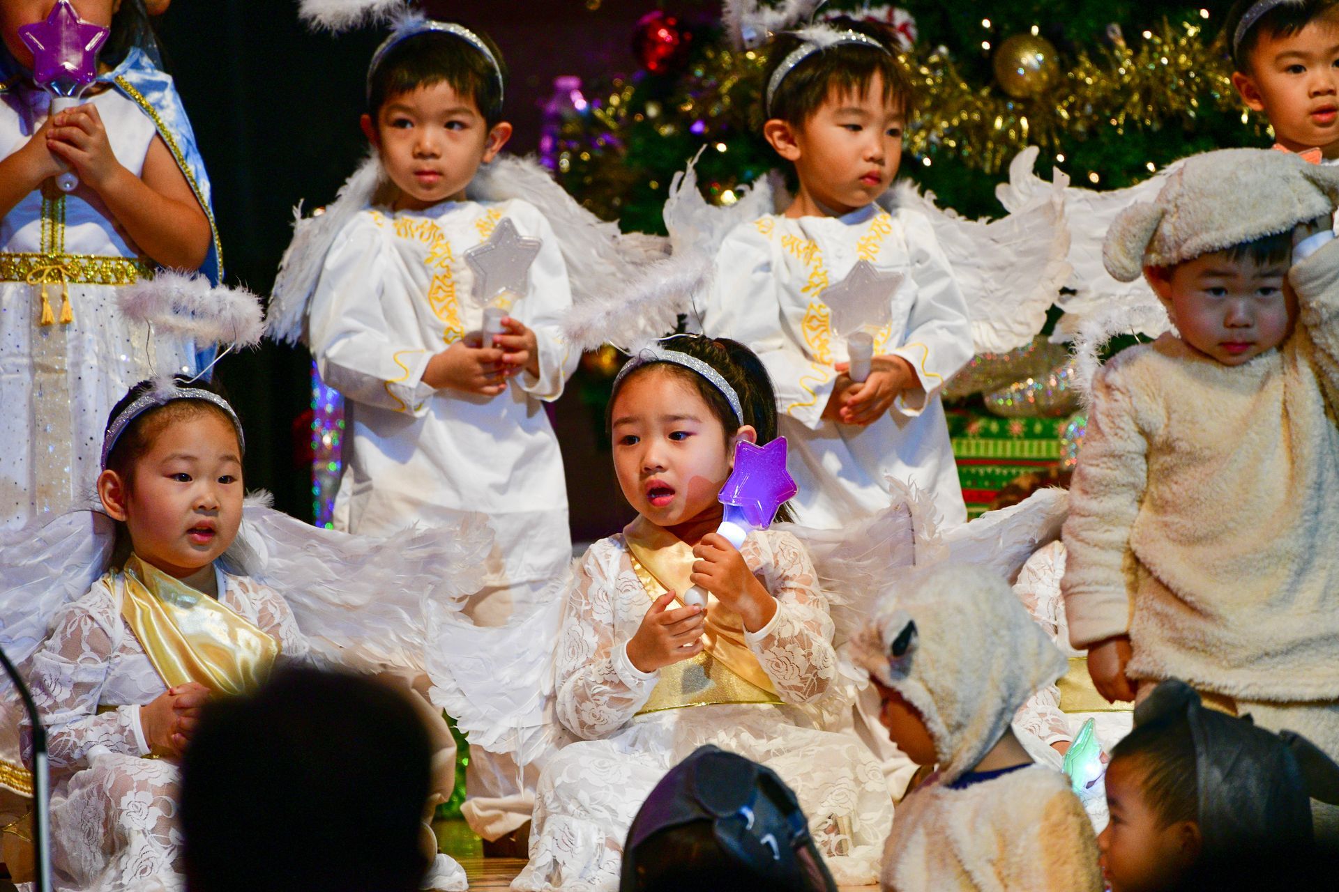 Children in angel and animal costumes perform onstage at Christmas.