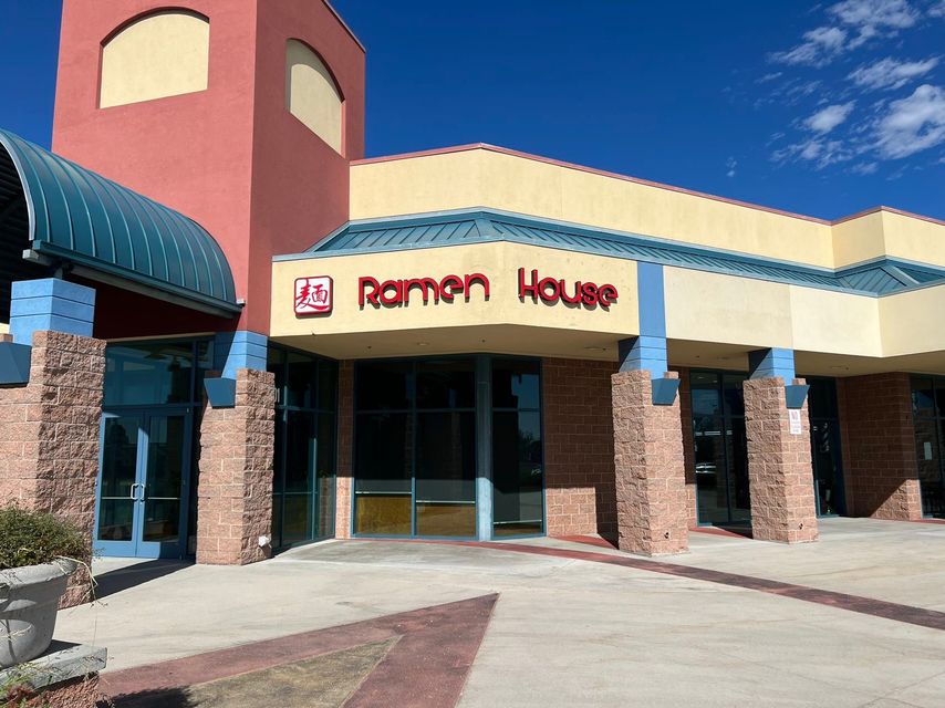 Raymond House storefront with brick columns and a curved blue awning under a clear sky