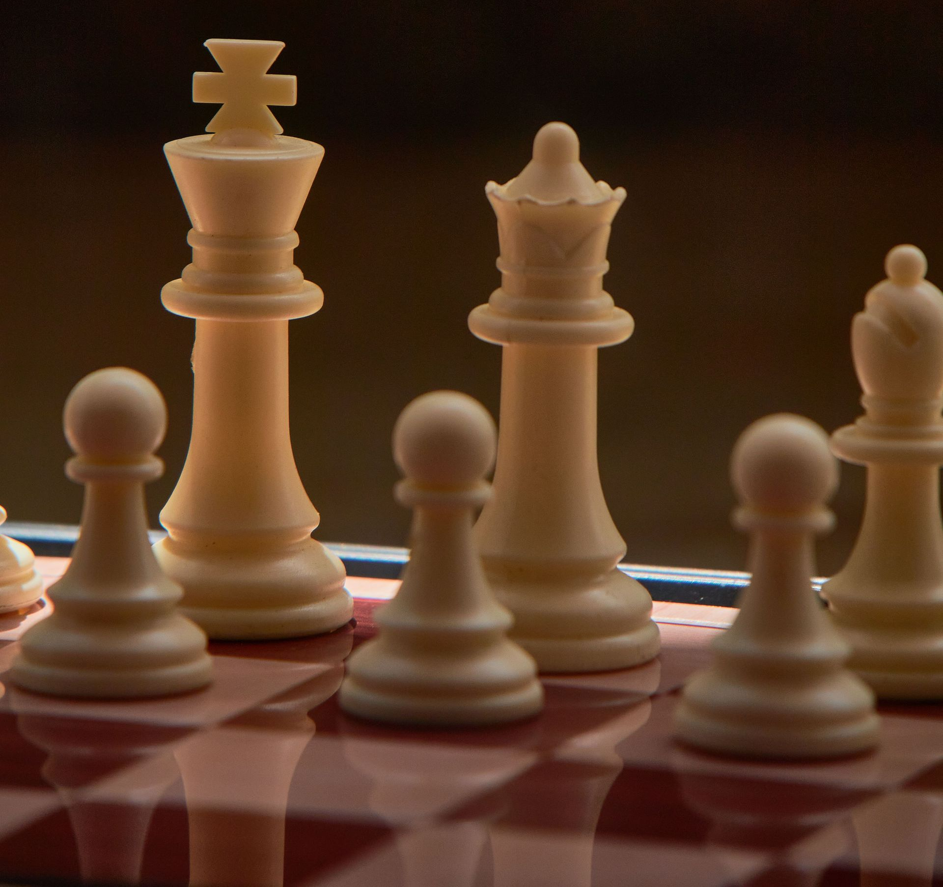 White chess pieces on a red board, with a king and pawns in warm dramatic light