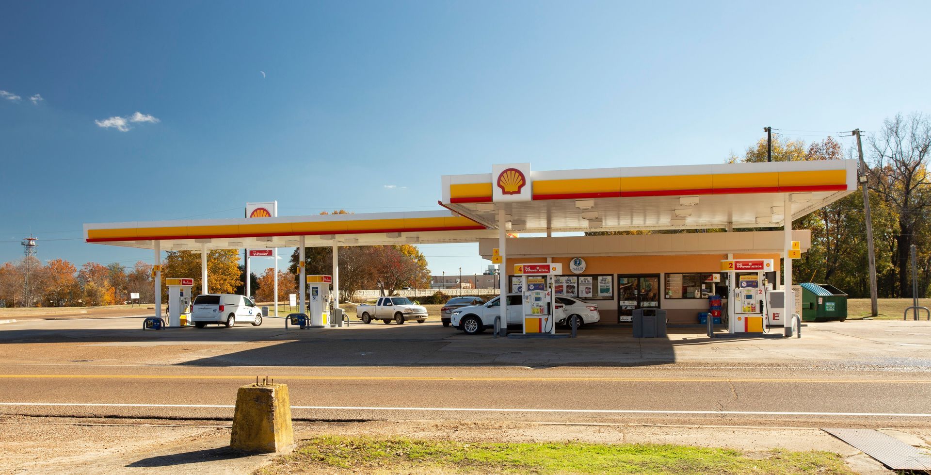 A gas station with cars parked in front of it on a sunny day.