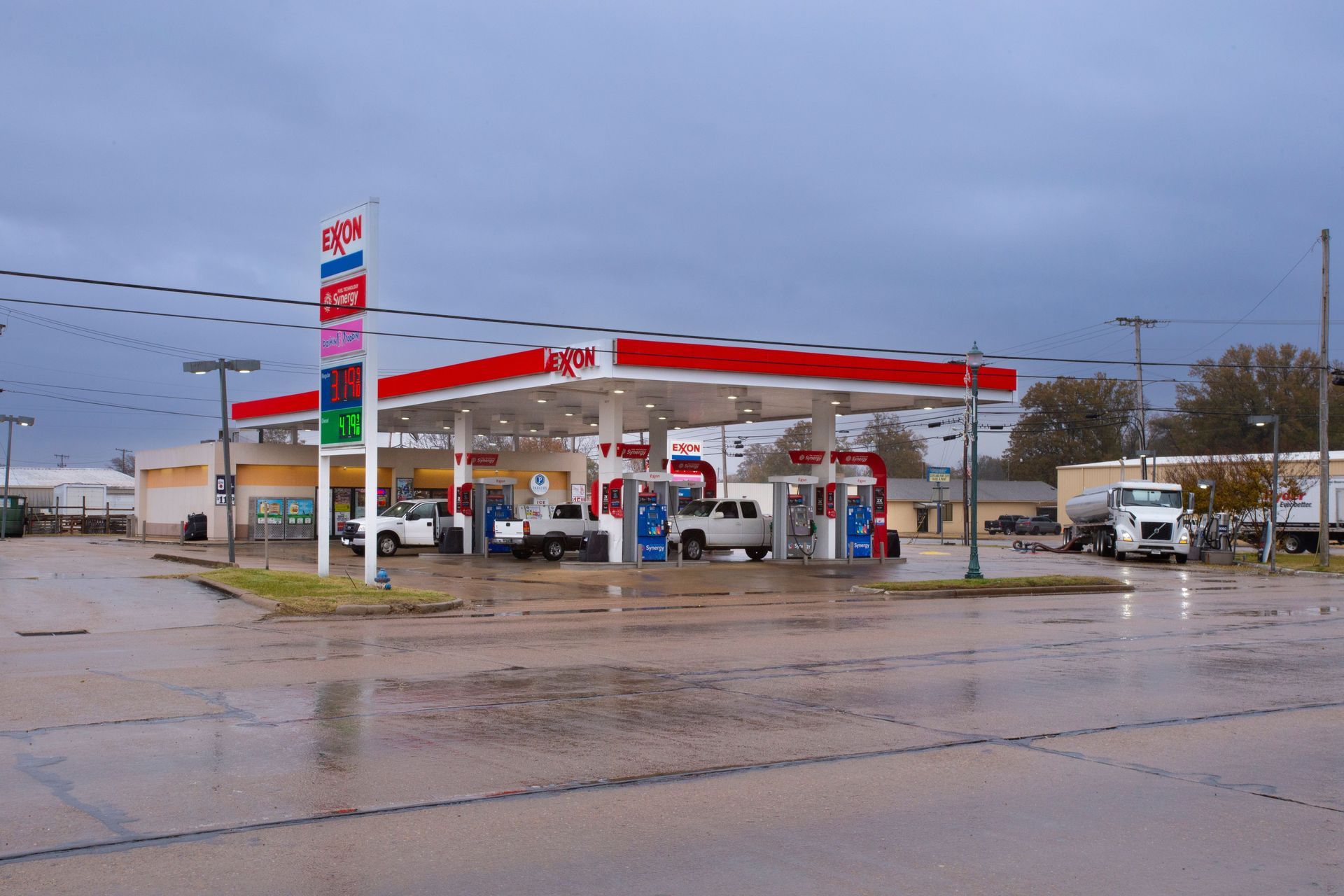 A gas station with cars parked in front of it on a rainy day.
