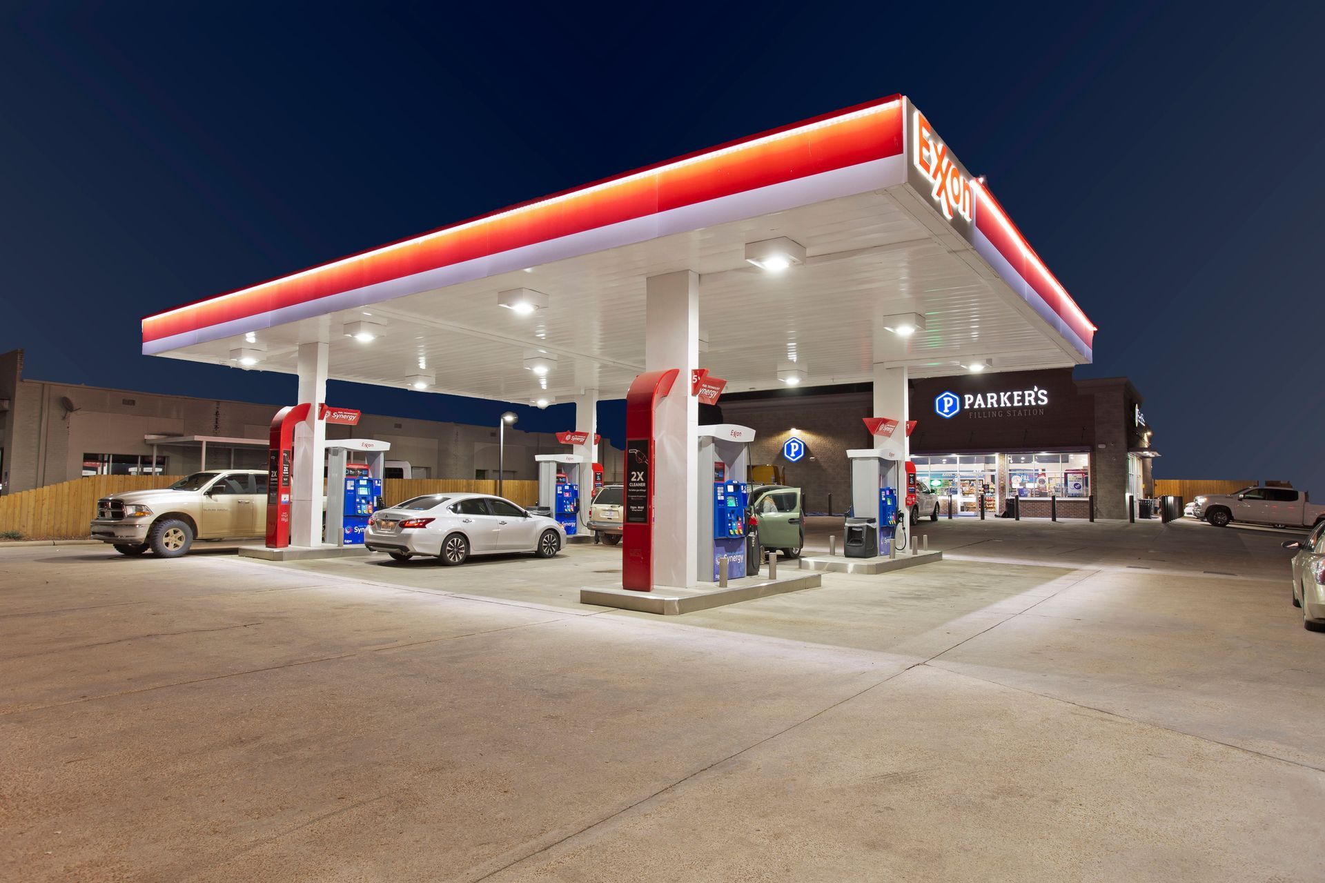 A gas station with cars parked in front of it at night