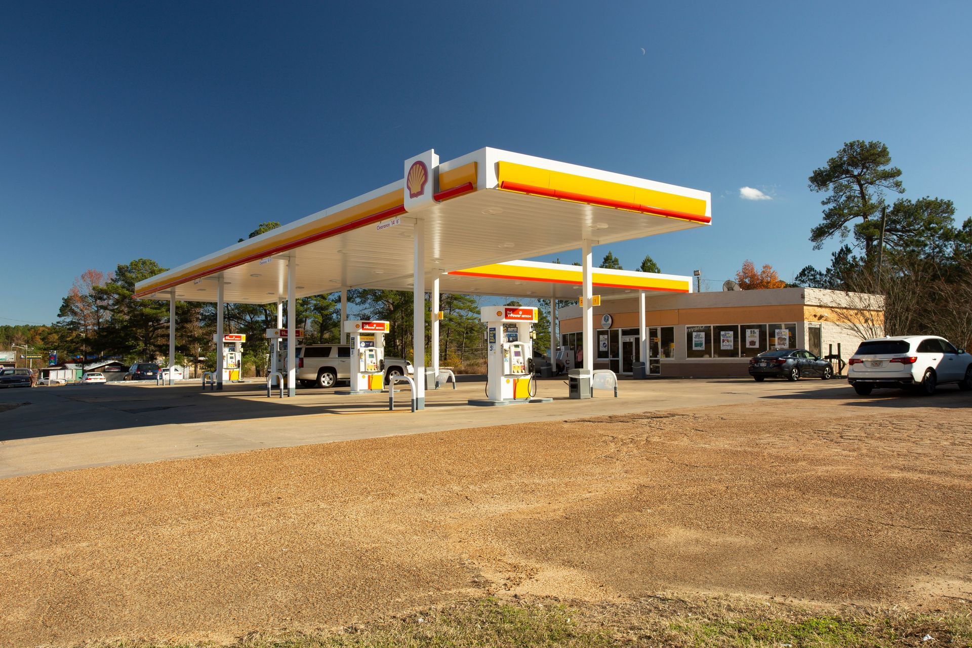 A gas station with cars parked in front of it on a sunny day.