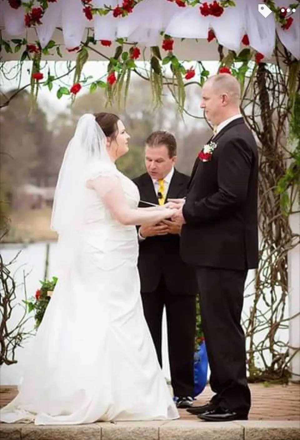 A bride and groom are holding hands during their wedding ceremony.
