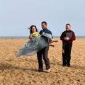 A man is carrying a woman in a wedding dress on the beach.