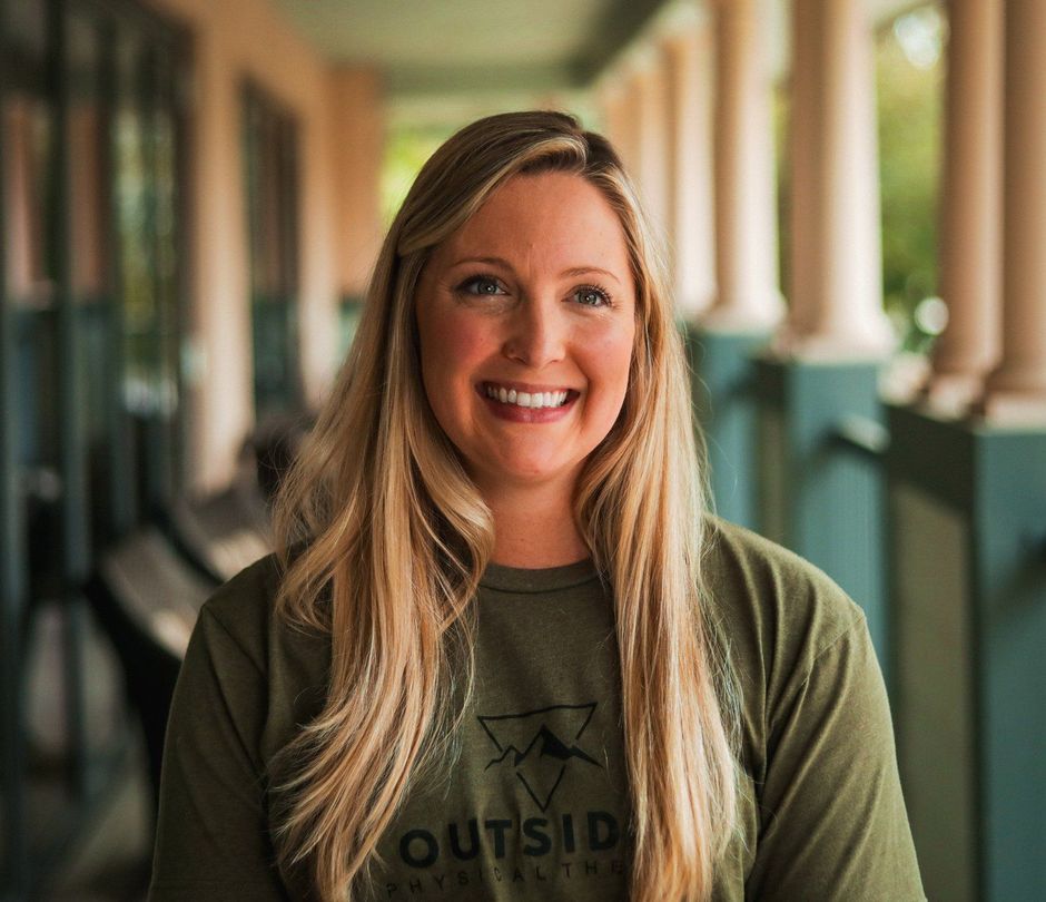 A woman wearing a green shirt is smiling for the camera.