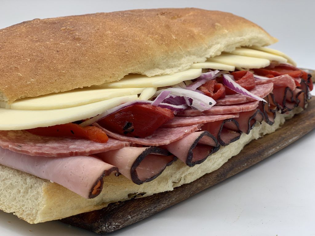 A sub sandwich is sitting on a wooden cutting board.