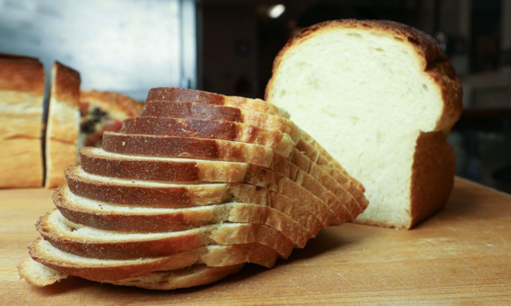 A loaf of bread that has been sliced on a cutting board