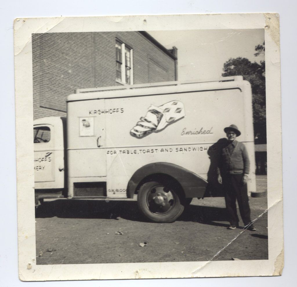 A black and white photo of a man standing next to a sandwich truck