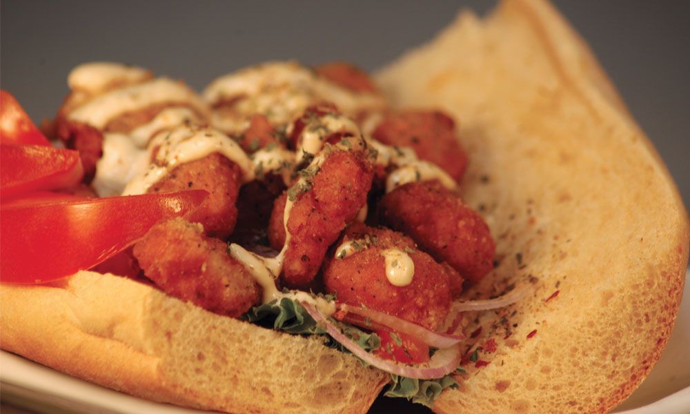 A close up of a shrimp po boy sandwich on a plate.