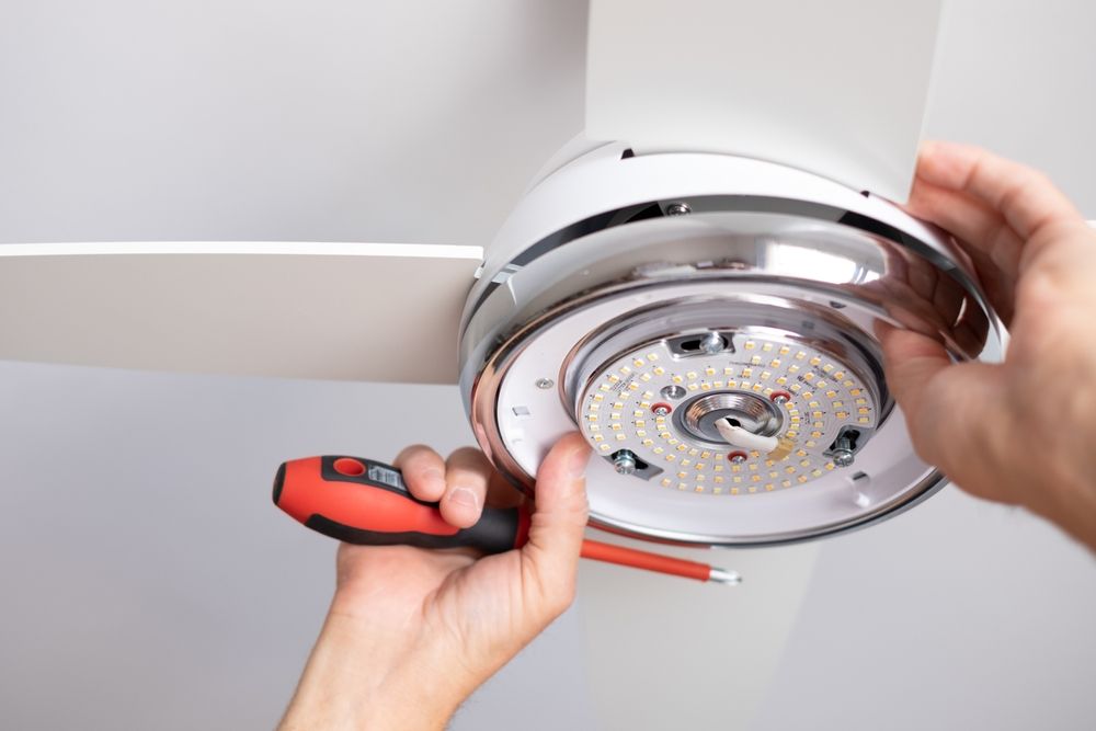 Hands Installing a Ceiling Fan Light Fixture — Grant Murphy Electrical in Tweed Heads, NSW