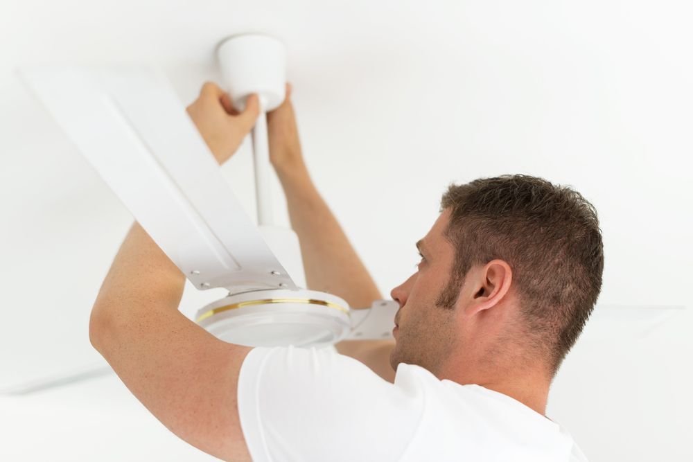 Man in a White Shirt Installing a White Ceiling Fan — Grant Murphy Electrical in Currumbin, QLD