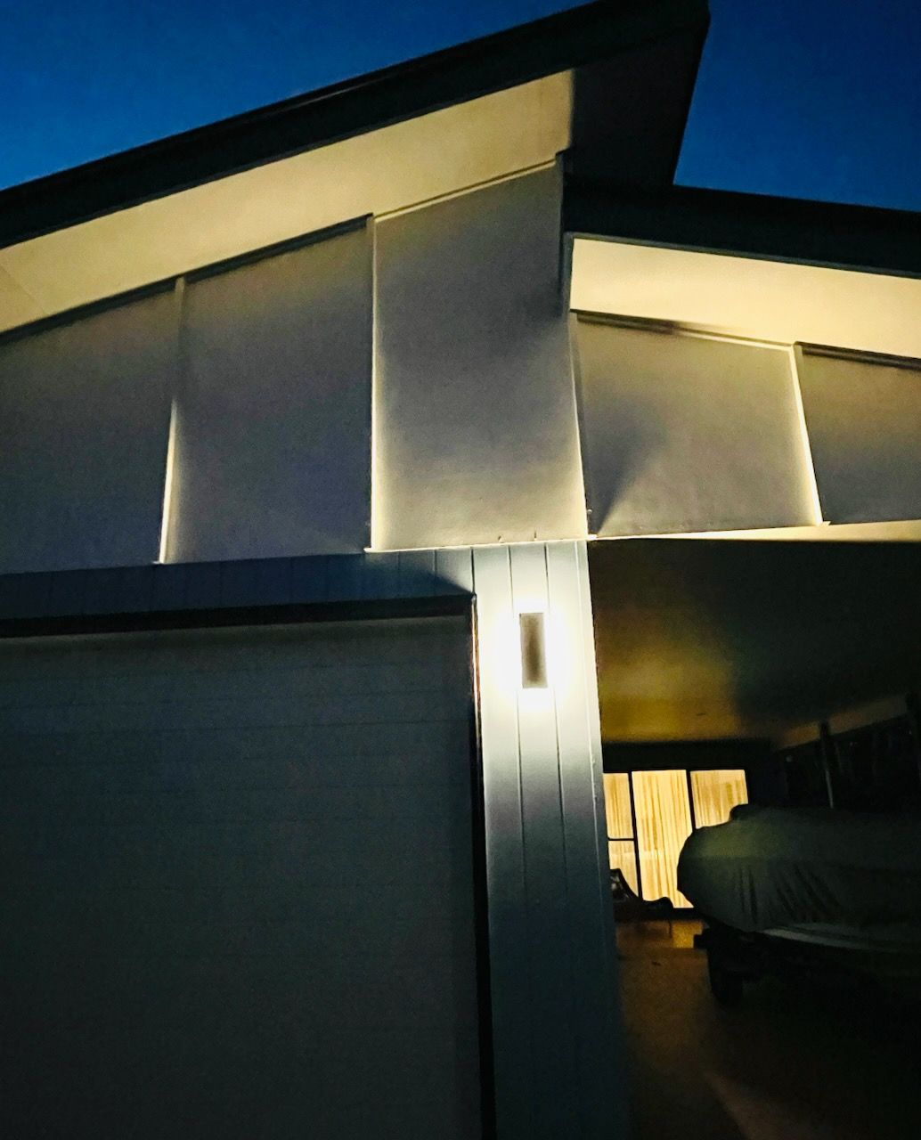 Exterior of a building lit at night; a wall with an embedded light and a peek inside a lit interior. — Grant Murphy Electrical in Kingscliff, NSW