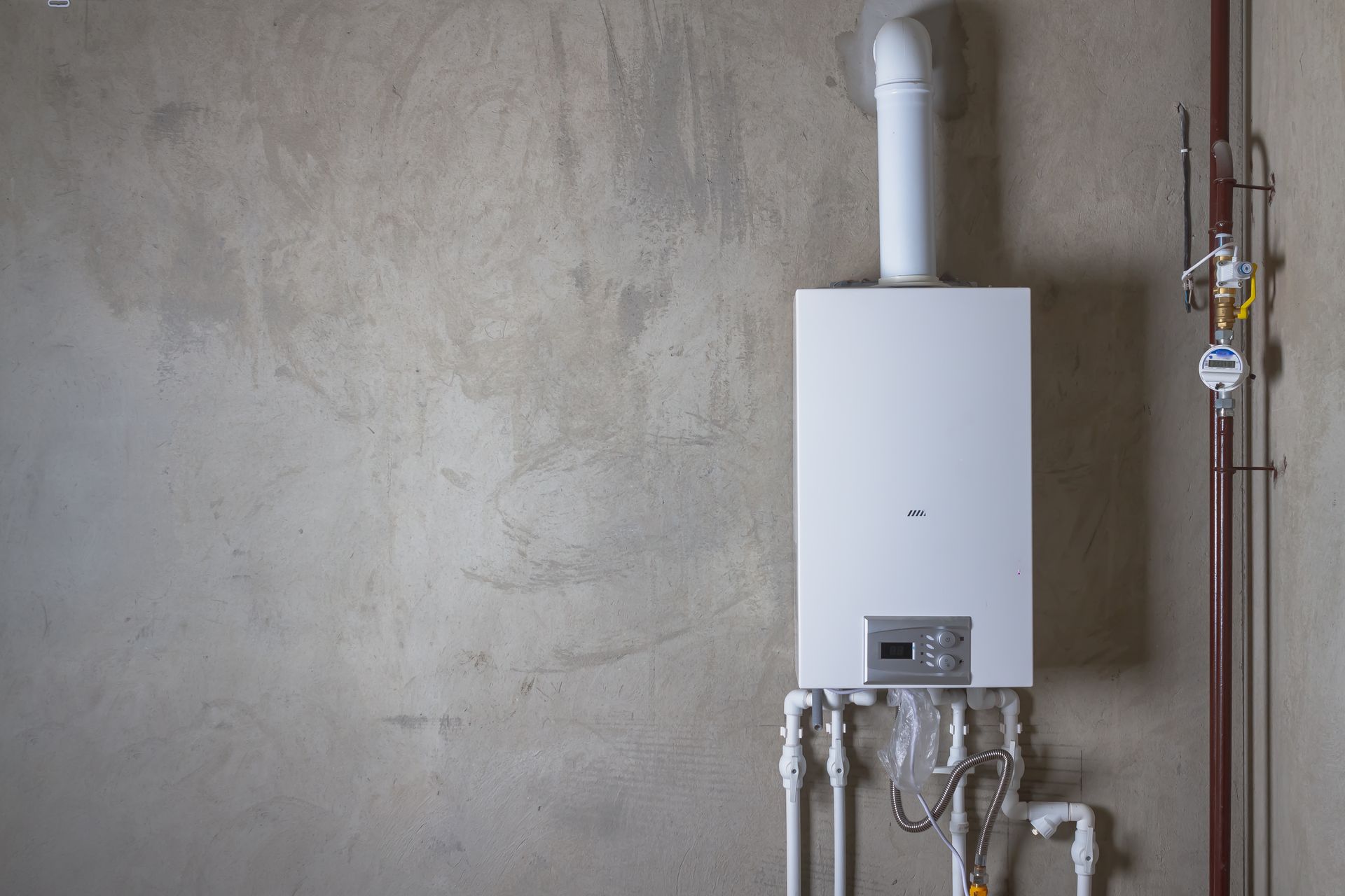 White boiler on a concrete wall with pipes and flue; indoor setting.