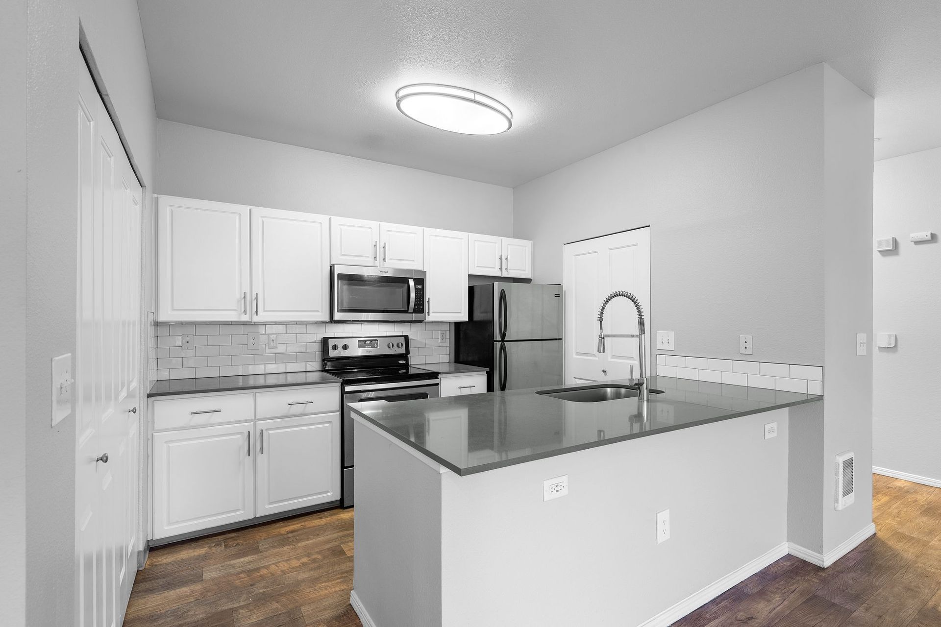 Modern kitchen with white cabinets, stainless steel appliances, and gray countertops.