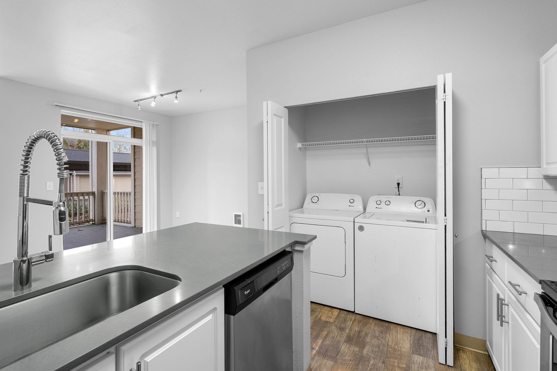 Kitchen with gray countertops, stainless steel appliances, and a laundry closet with open doors.