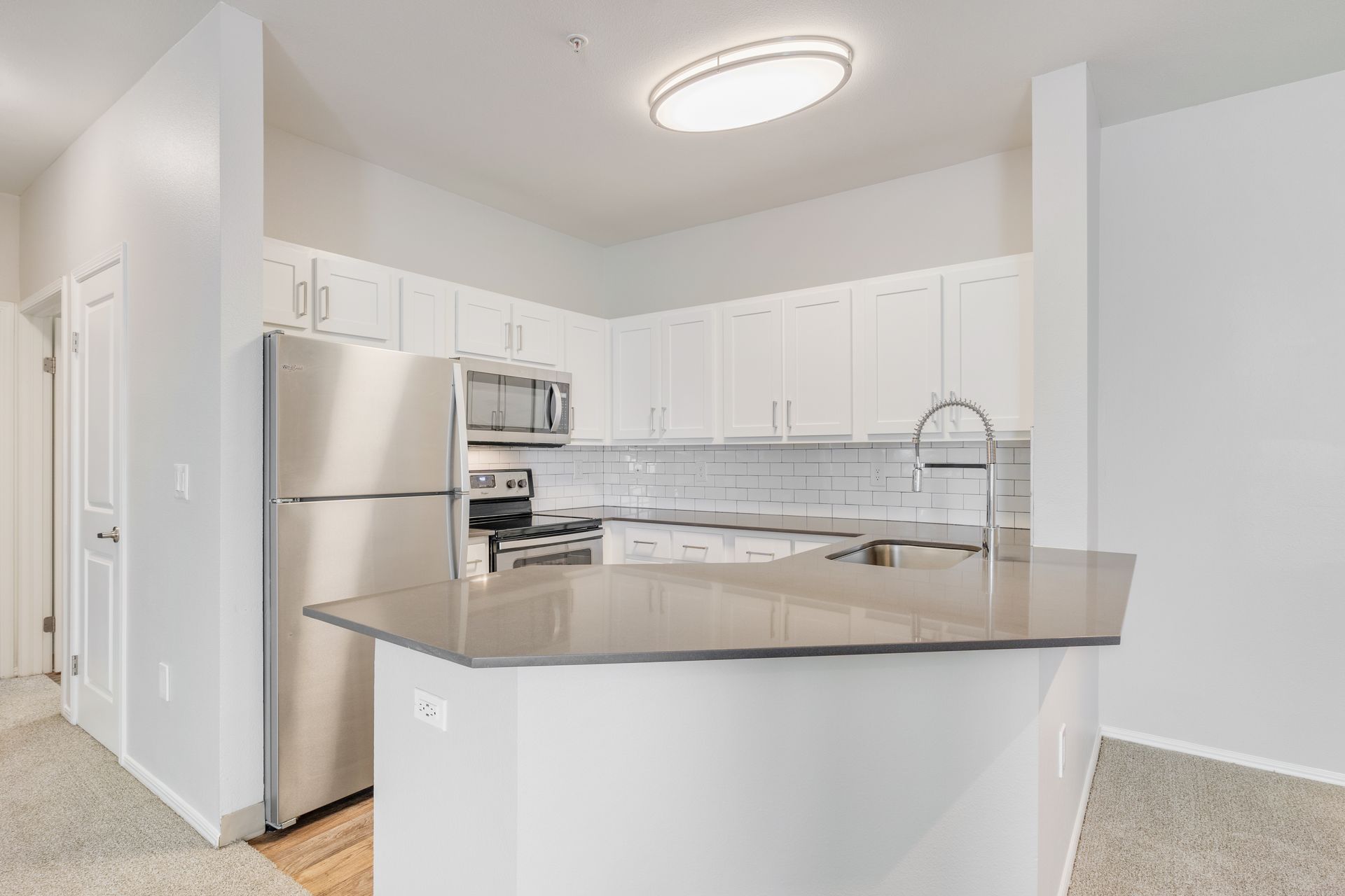 Bright kitchen with white cabinets, stainless steel appliances, and a gray island countertop.