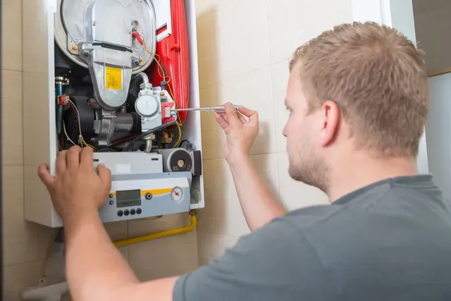 A man is fixing a boiler with a wrench.