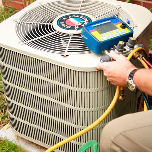 A man is working on an air conditioner with a hose attached to it.