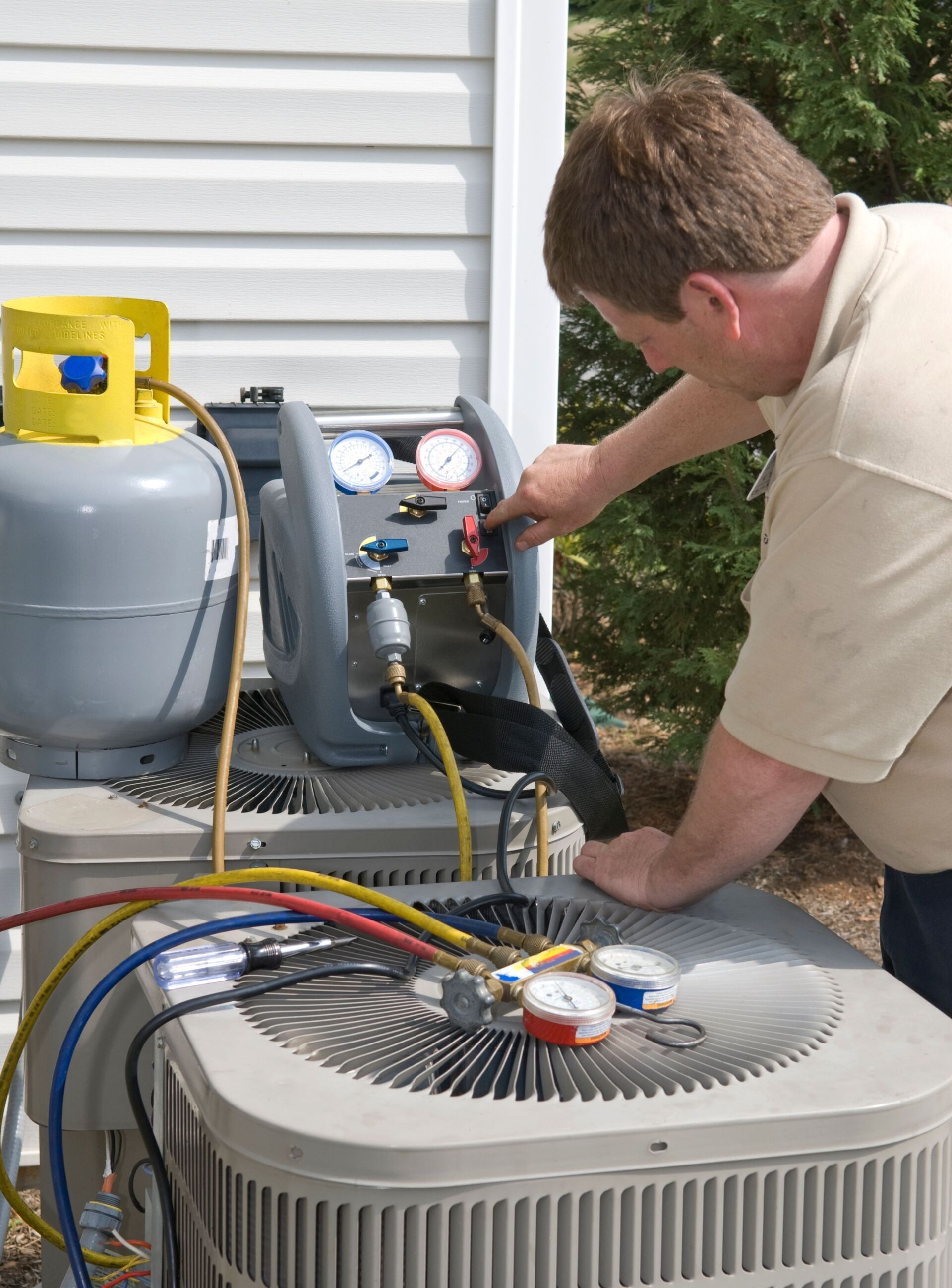 A man is working on an air conditioner outside of a house