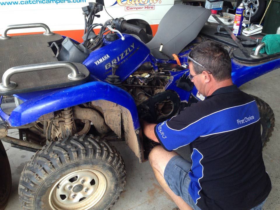 A Man is Working on a Yamaha ATV in a Garage — Cairns Auto Electrical Mechanical Air & Audio in Innisfail, QLD