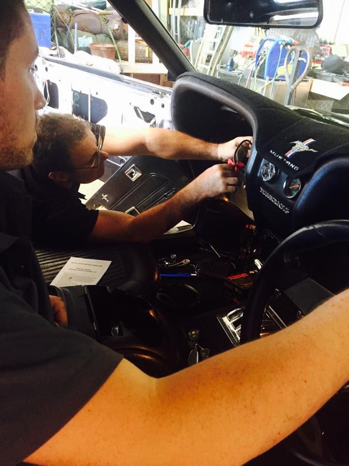 Two Men Are Working on the Dashboard of a Car — Cairns Auto Electrical Mechanical Air & Audio in Stratford, QLD