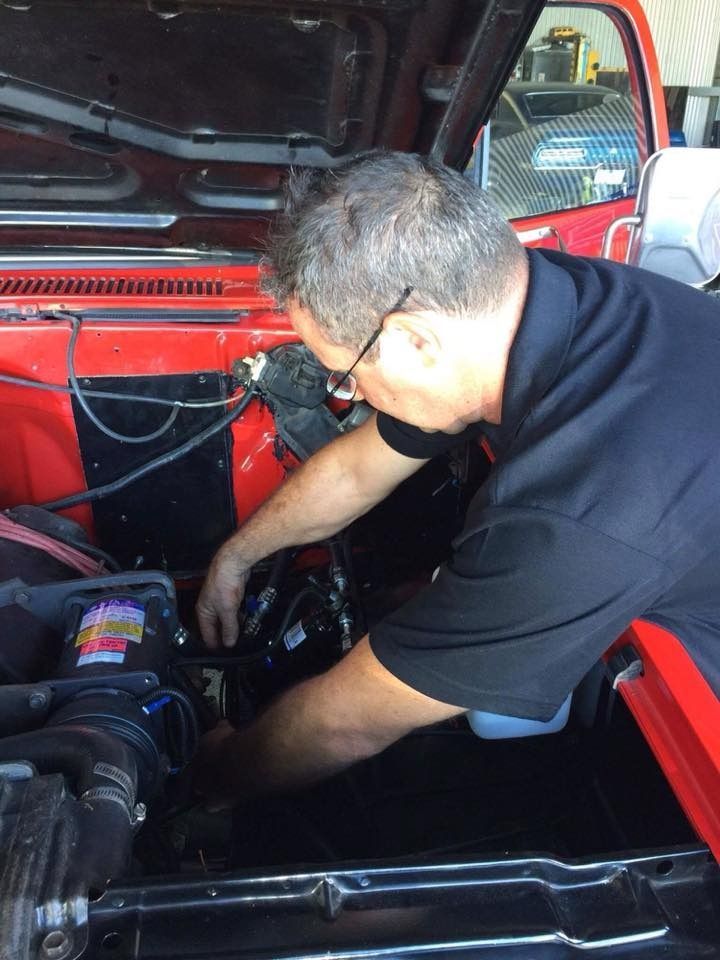 Mechanic Working Under the Hood of Red Car