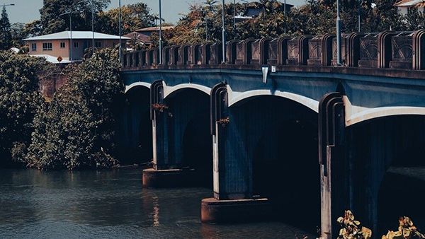 A Bridge Over a Body of Water With a House in the Background — Cairns Auto Electrical Mechanical Air & Audio in Mareeba, QLD