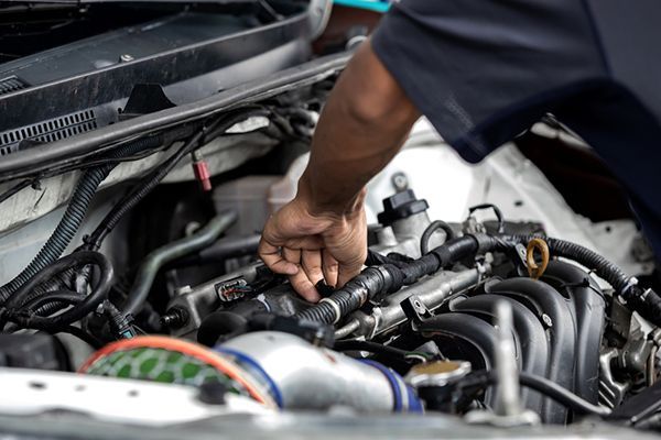 A Man is Working on the Engine of a Car With a Wrench — Cairns Auto Electrical Mechanical Air & Audio in Mareeba, QLD