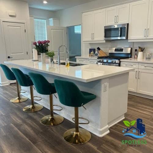 Modern kitchen with white island, teal barstools, stainless appliances, and a vase of flowers