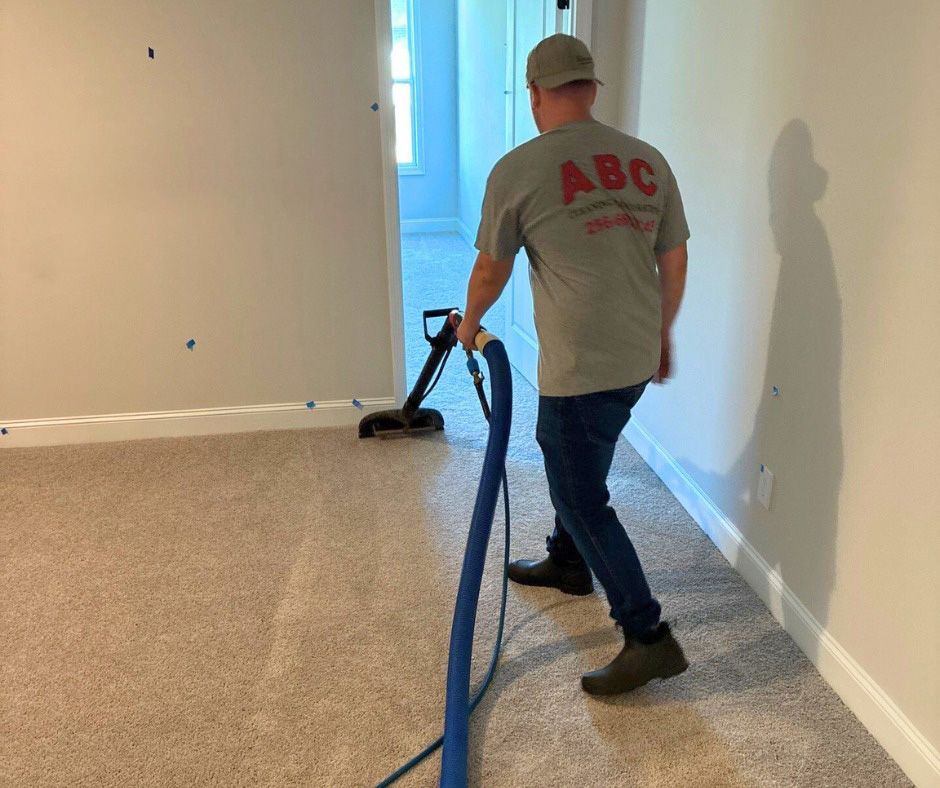 A person cleaning carpet in a room with a vacuum cleaner.