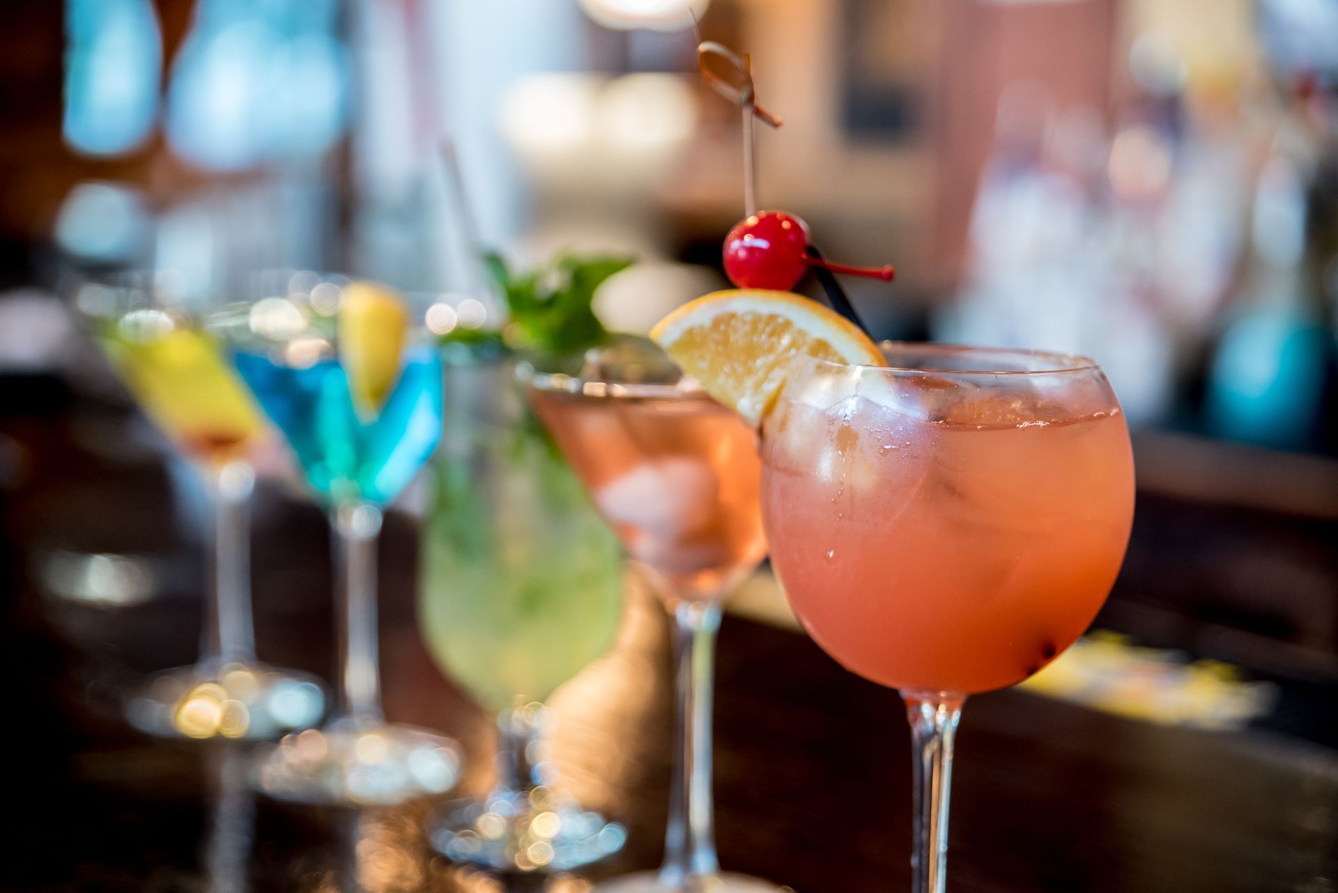 Colorful cocktails with garnish on a bar counter in a dimly lit lounge