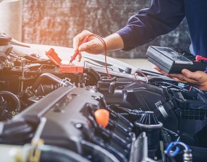 Mechanic checking a car engine with a dipstick under the hood