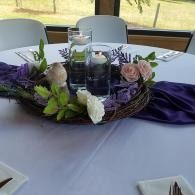 Purple floral centerpiece on a banquet table with white chairs in the background