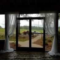 Curtained glass doors open to a garden path and rural field beyond