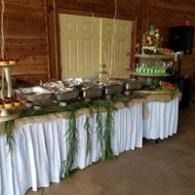 Buffet table with white tablecloths and green garland in a wood-paneled room