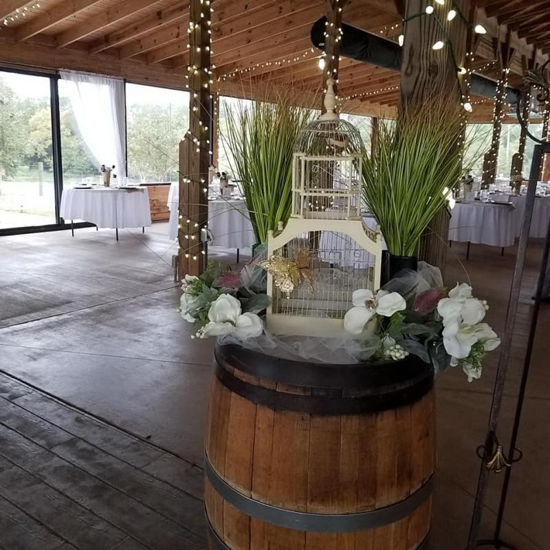 Wedding reception decor with white birdcage centerpiece on a barrel.