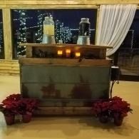 Small altar or display table with candles, flowers, and a white curtain with lights continuing outside.
