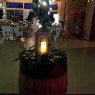 Lantern candle centerpiece on a barrel in a warmly lit banquet hall with tables in the background
