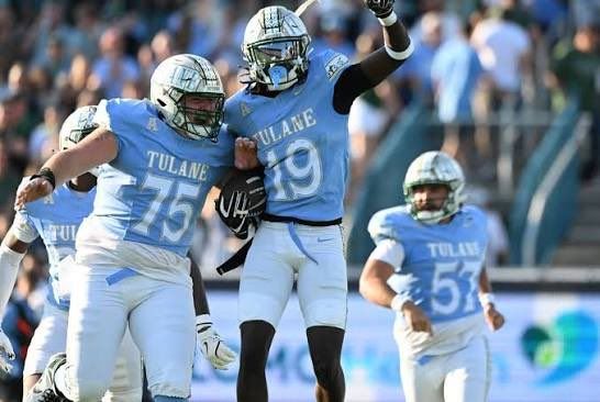 Tulane football players in white and blue uniforms celebrate on the field during a game