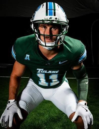 Football player in green Titans uniform crouching on turf, wearing helmet and gloves