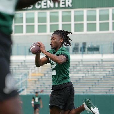 Football player in green jersey catching a pass during practice on a field