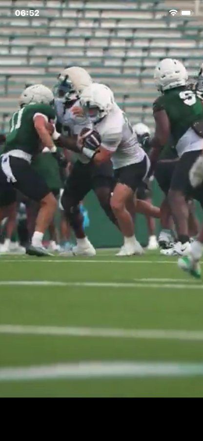 Football players in green and white uniforms colliding during a play on a field