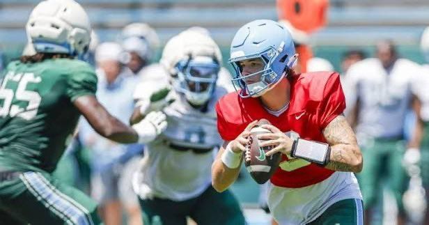 Football player in red jersey catches a pass while defenders close in on the field