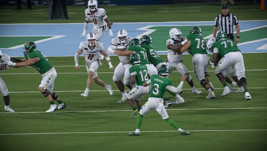 Football players in green and white battling on a wet field during a game